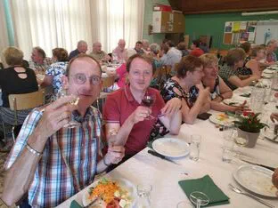 Koorleden klinken samen aan tafel tijdens een etentje