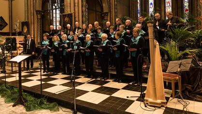 Het koor in concertkledij op het podium tijdens het winterconcert, met een harp vooraan